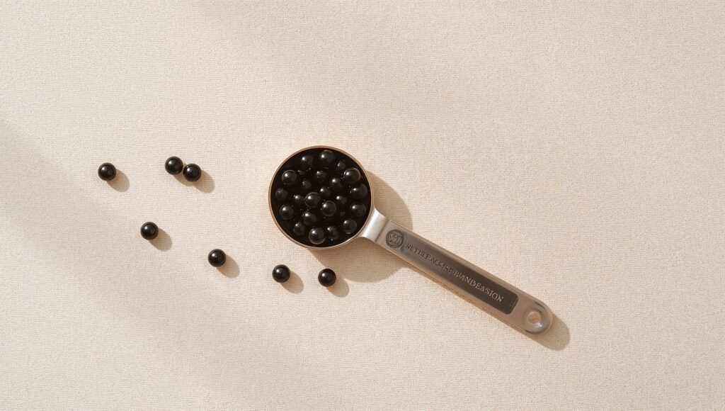 Half scoop of tapioca pearls in a small measuring spoon on a bright tabletop