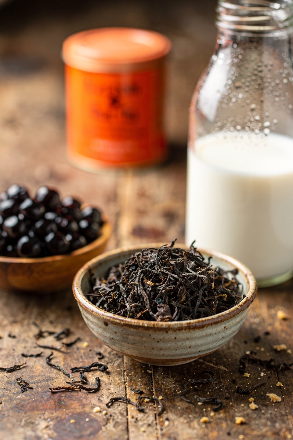 Thai milk tea ingredients with black tea leaves, boba pearls, milk, and Thai tea mix