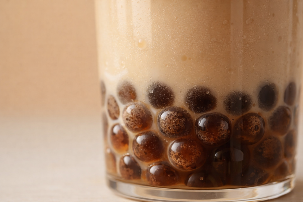 Close-up of tapioca boba pearls in milk tea showing translucent texture and glass base