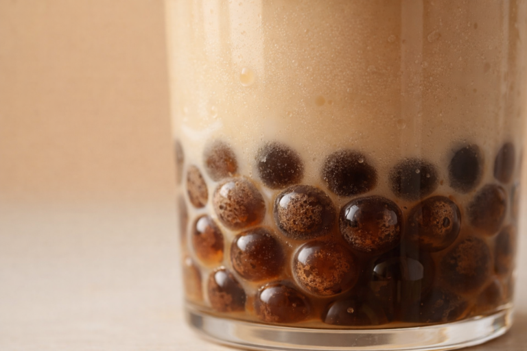 Close-up of tapioca boba pearls in milk tea showing translucent texture and glass base