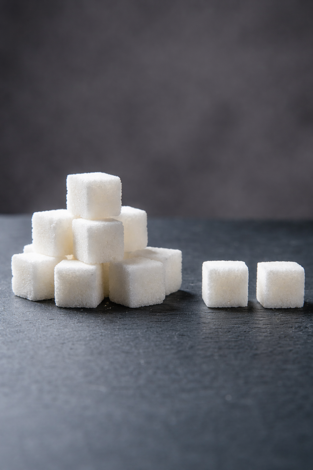 White sugar cubes arranged on a dark surface to show bubble tea sugar levels