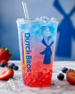 Does Dutch Bros have boba? A Dutch Bros iced drink with red popping boba pearls, blue and pink layers, ice, and berries.