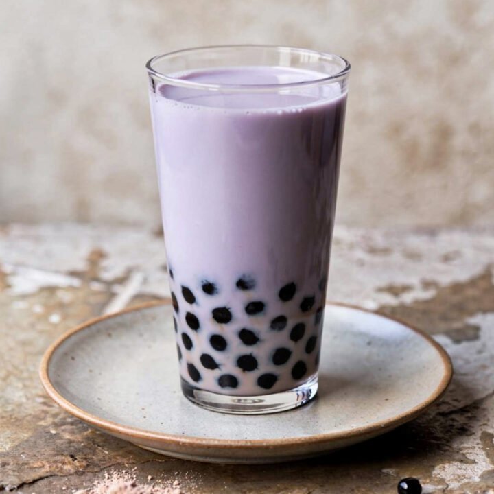 classic taro milk tea with black tapioca pearls in a glass on a plate