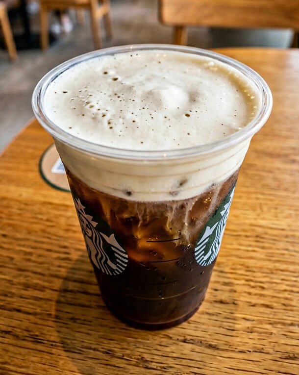 Close-up of Starbucks cold foam on top of an iced coffee in a branded cup