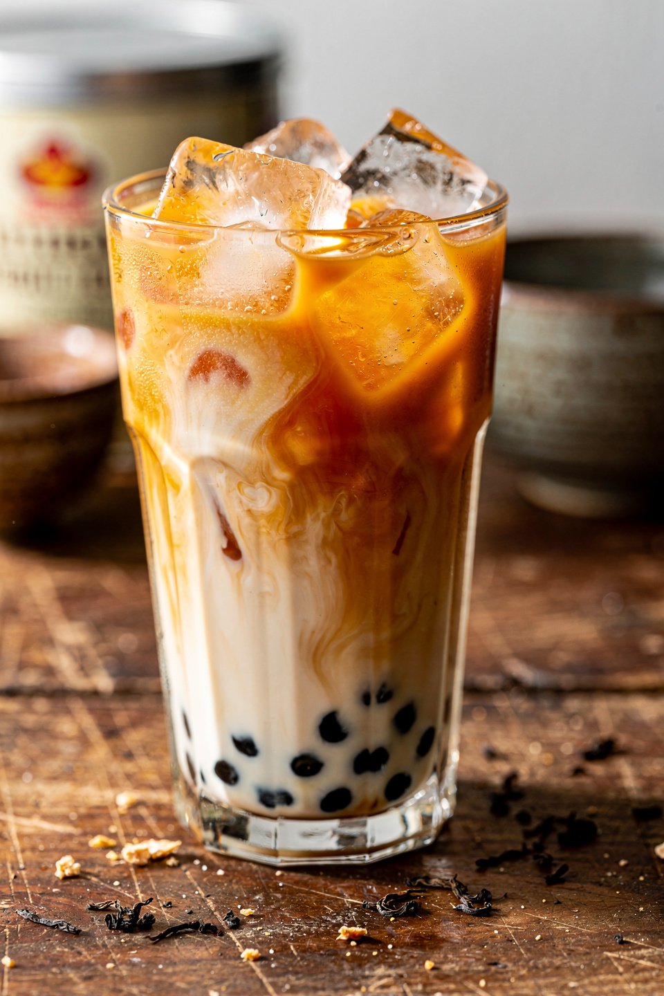 close-up Thai milk tea with boba, ice, and creamy milk swirls