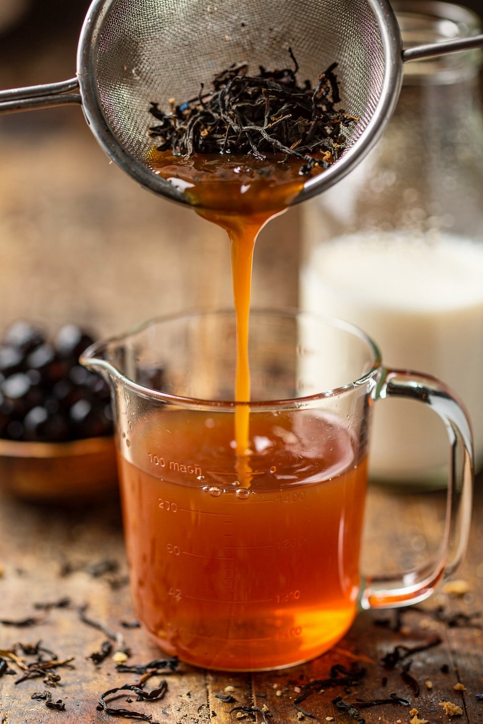 Thai tea being strained into a measuring cup for homemade Thai milk tea
